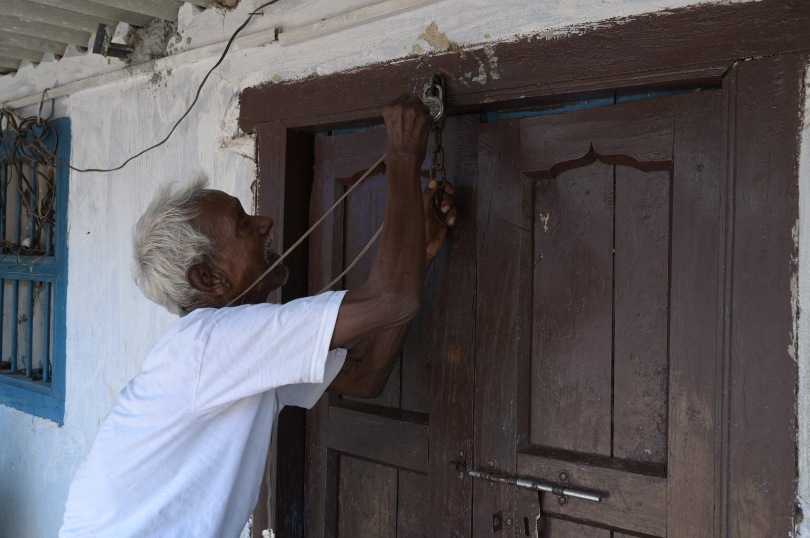 Sukhram Munda, Grandson of Birsa Munda opening the door of his small
shop's gate.